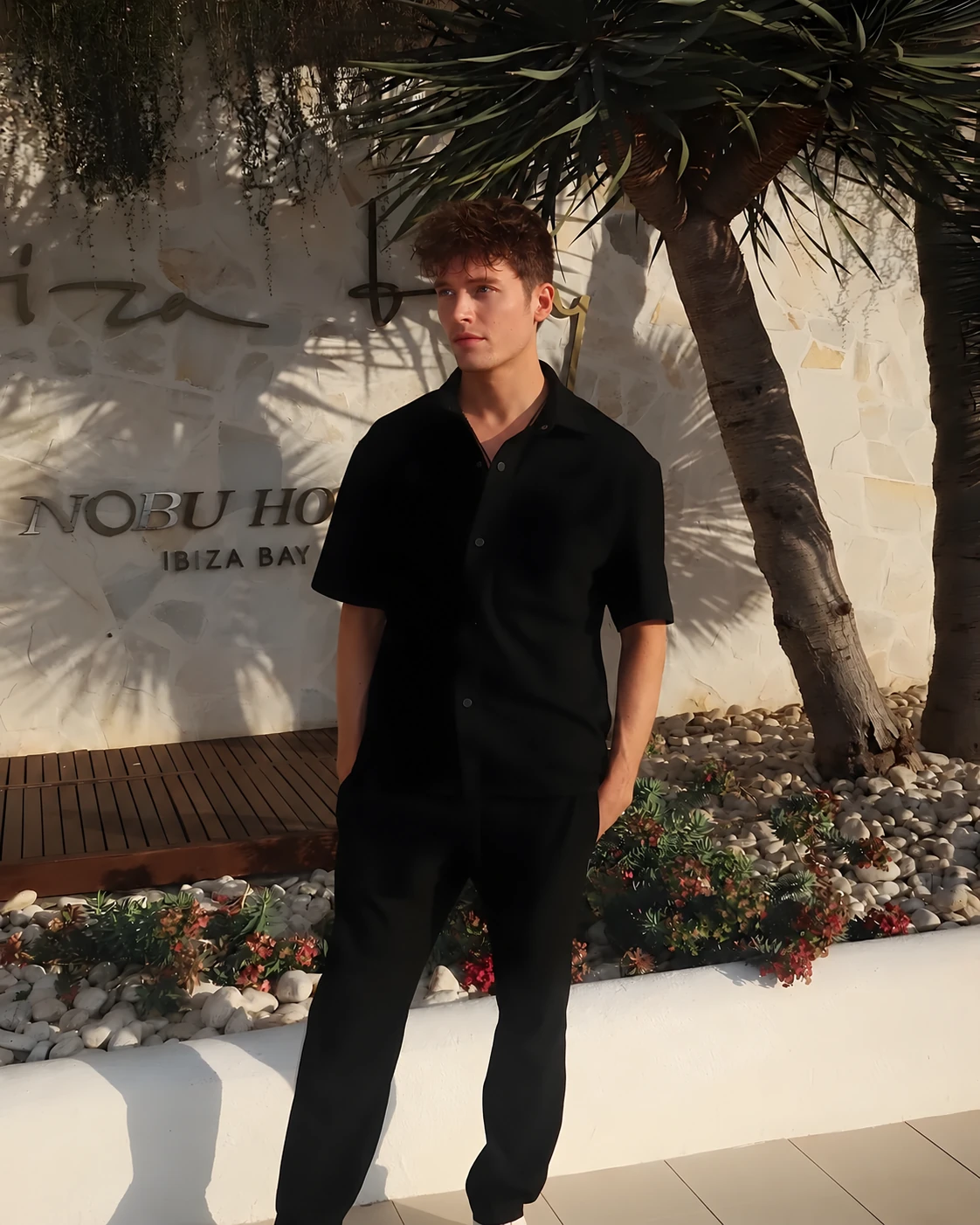 Joe Garth in Ibiza, dressed in black, under palm trees